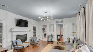 Una sala de estar moderna con chimenea, televisor montado en la pared y comedor con mesa y sillas.
