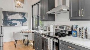 Een moderne keuken met donkergrijze kastjes, roestvrijstalen apparatuur en geometrische hanglampen.