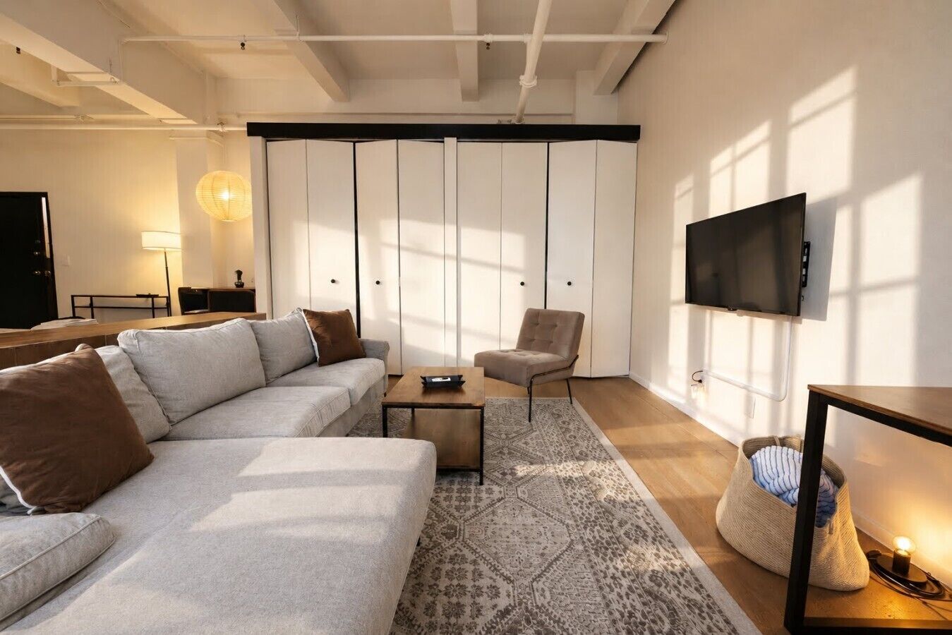 A modern living room with a sofa, armchair, coffee table, and a television mounted on the wall.