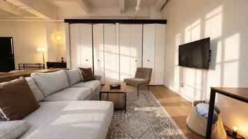 A modern living room with a sofa, armchair, coffee table, and a television mounted on the wall.