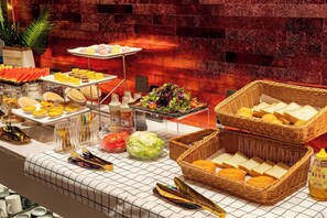 Un bufé con diferentes opciones de comida, incluyendo pasteles, ensaladas y pan.