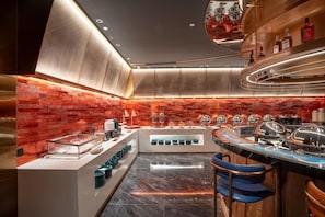 A modern kitchen with a brick wall backsplash, stainless steel appliances, and a bar area with stools. - Echerm Hotel Wuyangcun Metro Station (Guangzhou)