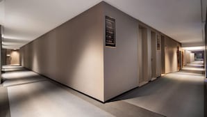 Un pasillo moderno de hotel con un cartel en la pared central que indica los servicios y direcciones.