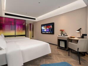 A modern hotel room with a large bed, a desk with a chair, a television mounted on the wall, and a small seating area with a table and a vase of flowers. - Echerm Hotel Wuyangcun Metro Station (Guangzhou)