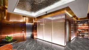 Un vestíbulo moderno con piso de mármol, una división de vidrio y un área de estar con una planta.