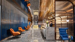 A modern hotel lobby with a long reception desk, seating area with orange and blue chairs, and a marble floor. - Echerm Hotel Wuyangcun Metro Station (Guangzhou)