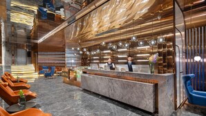 A modern hotel lobby with a reception desk, seating area, and a decorative ceiling. - Echerm Hotel Wuyangcun Metro Station (Guangzhou)