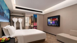A modern hotel room with a large bed, a seating area, a TV on the wall, and a view of the outside. - Echerm Hotel Wuyangcun Metro Station (Guangzhou)