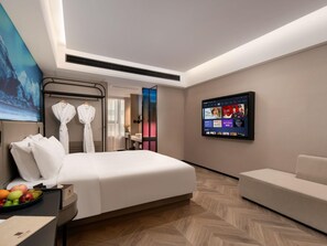 A modern hotel room with a large bed, a seating area, a TV on the wall, and a view of the outside. - Echerm Hotel Wuyangcun Metro Station (Guangzhou)