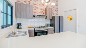 A modern kitchen with a gas stove, microwave, and stainless steel refrigerator. - Casa Quijano 06 By Wynwood House (Panama City)