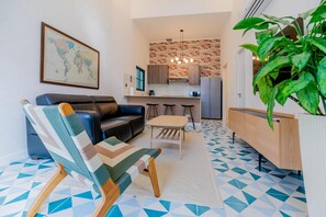 A compact living space with a sofa, a dining table, and a kitchen area. - Casa Quijano 06 By Wynwood House (Panama City)
