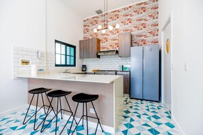 A modern kitchen with a central island, bar stools, a refrigerator, and a patterned backsplash. - Casa Quijano 06 By Wynwood House (Panama City)