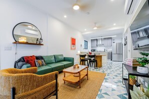 A modern apartment with a green sofa, a small dining table, and a kitchen area. - Casa Quijano 06 By Wynwood House (Panama City)