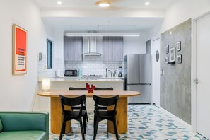 A compact kitchen with modern appliances, a dining area with two chairs, and a patterned floor. - Casa Quijano 06 By Wynwood House (Panama City)