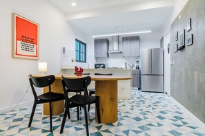 A modern kitchen with a central island, black chairs, a red decorative piece, and a geometric patterned floor. - Casa Quijano 06 By Wynwood House (Panama City)