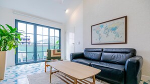 A modern room with a black leather sofa, a wooden coffee table, and a large world map on the wall. - Casa Quijano 06 By Wynwood House (Panama City)