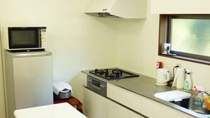 Una cocina compacta con microondas, estufa, lavaplatos y una ventana sobre el lavaplatos.
