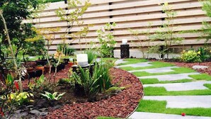 Un jardín con un sendero de piedra, césped verde y diversas plantas.
