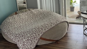 Une pièce dotée d’une grande fenêtre, d’un lit recouvert d’un couvre-lit à motifs léopard, d’un plancher en bois et offrant une vue sur une piscine à l’extérieur.