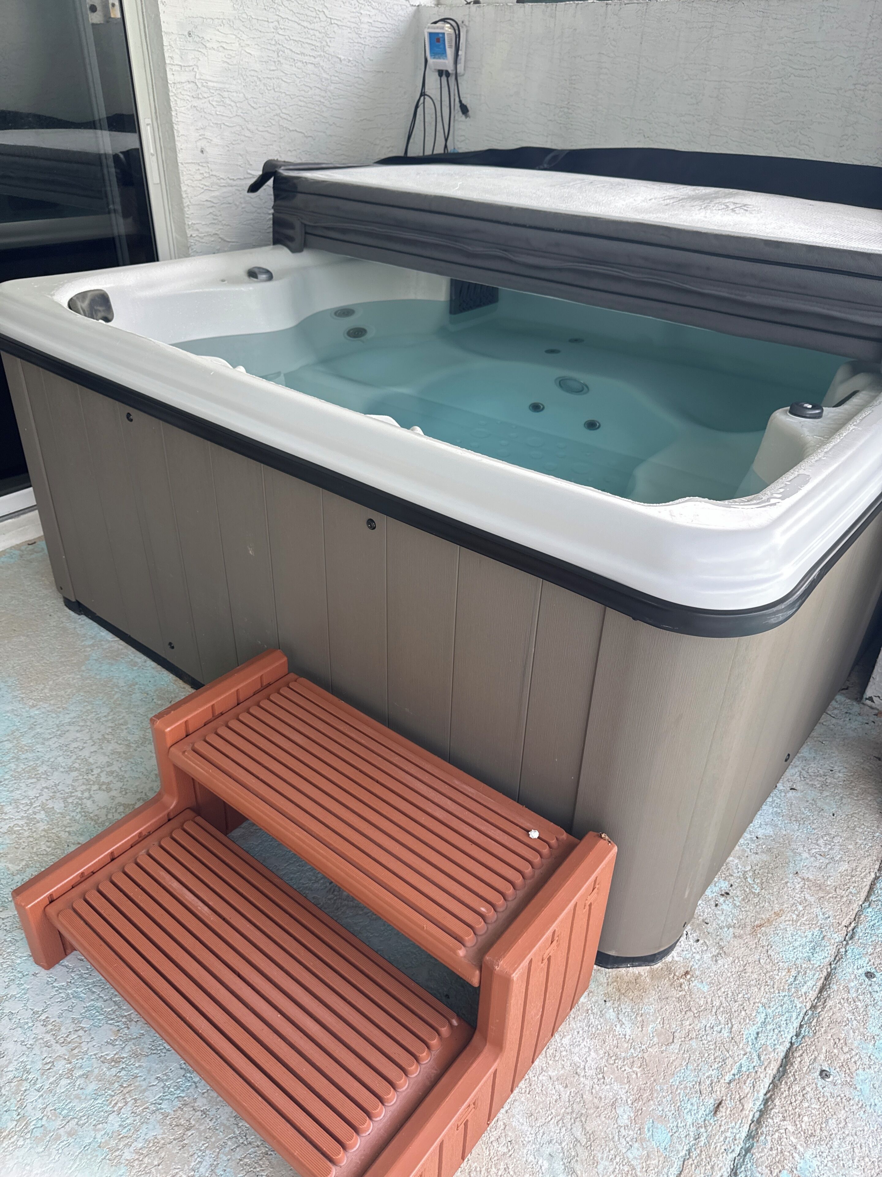 A hot tub with a wooden bench in front.