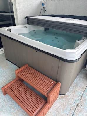 Ein Whirlpool mit einer hölzernen Sitzbank davor.