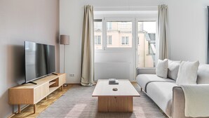 A modern living room with a flat-screen TV, wooden side table, sofa, and a coffee table. - Blueground | Währing, view, nr Türkenschanzpark (Vienna)