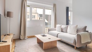 A modern living room with a sofa, a coffee table, and a TV on a wooden stand. - Blueground | Währing, view, nr Türkenschanzpark (Vienna)