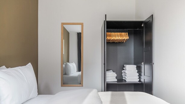 A hotel room with a bed, a mirror, and a wardrobe with neatly folded towels. - Blueground | Währing, view, nr Türkenschanzpark (Vienna)