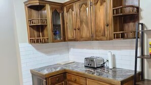 Una cocina con gabinetes de madera, encimera de mármol y un tostador empotrado.