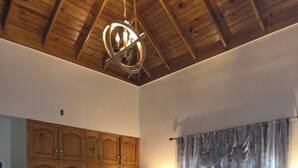 Un dormitorio con techo de madera, cama con ropa de cama floral, armario y cortinas.