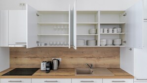 A modern kitchen with white cabinets, a wooden countertop, a sink, and various kitchen appliances. - Blueground | Innere Stadt, balcony, nr St. Stephen's Cathedral (Vienna)