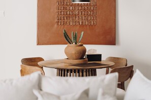Una mesa redonda de madera con una planta en maceta, dos sillas de madera y una lámpara de pared.