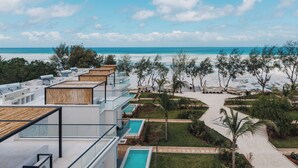 Un complexe hôtelier moderne doté de plusieurs piscines, offrant une vue sur la plage et abritant un jardin tropical.
