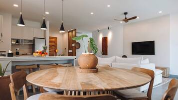 A modern kitchen with a central island, wooden chairs, and pendant lighting.
