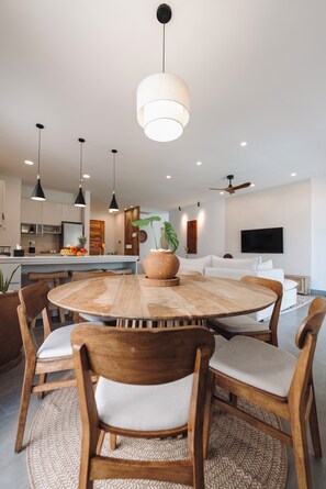 Una cocina moderna con una isla central, sillas de madera e iluminación colgante.