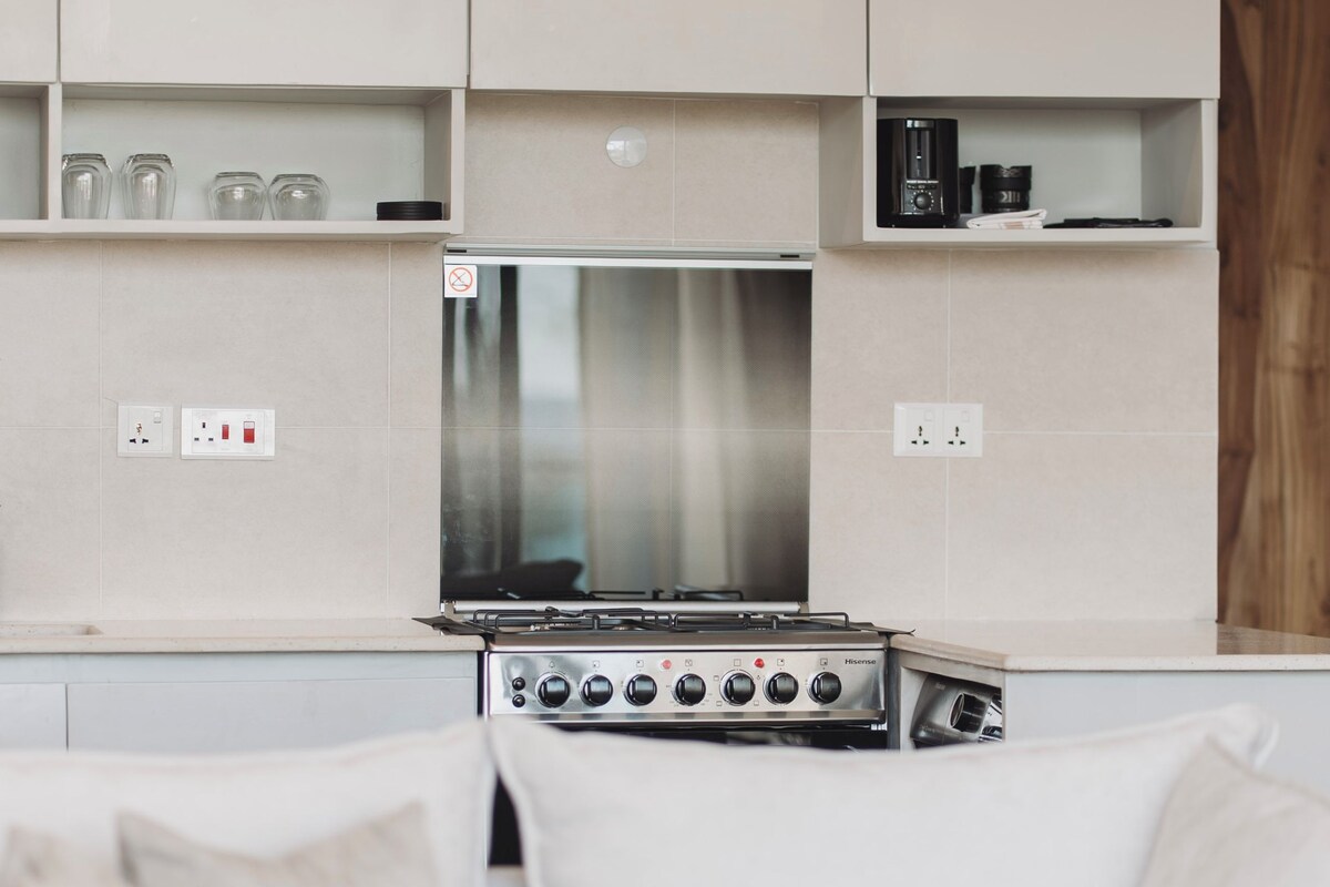 Una cocina moderna con estufa integrada, armarios blancos y encimera blanca.