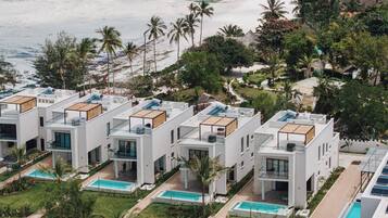 A modern resort with multiple white buildings, rooftop pools, and a beach view.