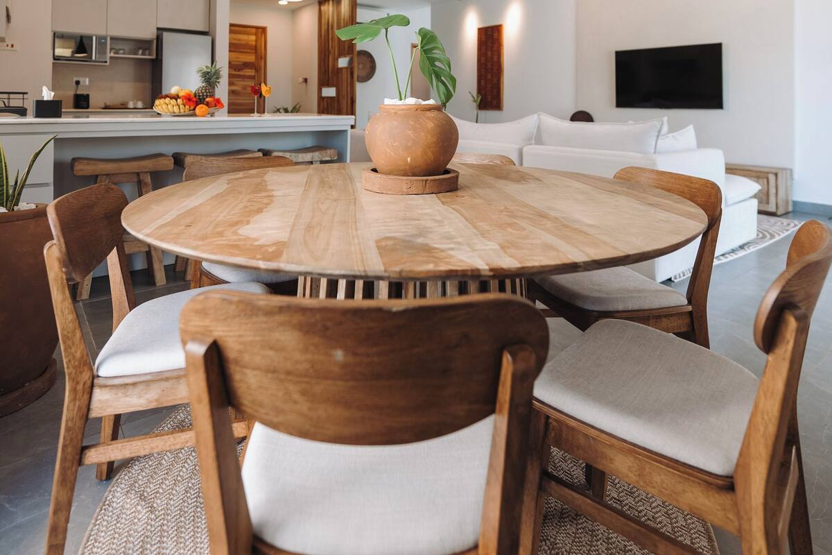Une cuisine moderne avec un îlot central, des chaises en bois et des luminaires suspendus.