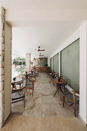 Un restaurante con una barra larga, sillas de madera y una pared de piedra.