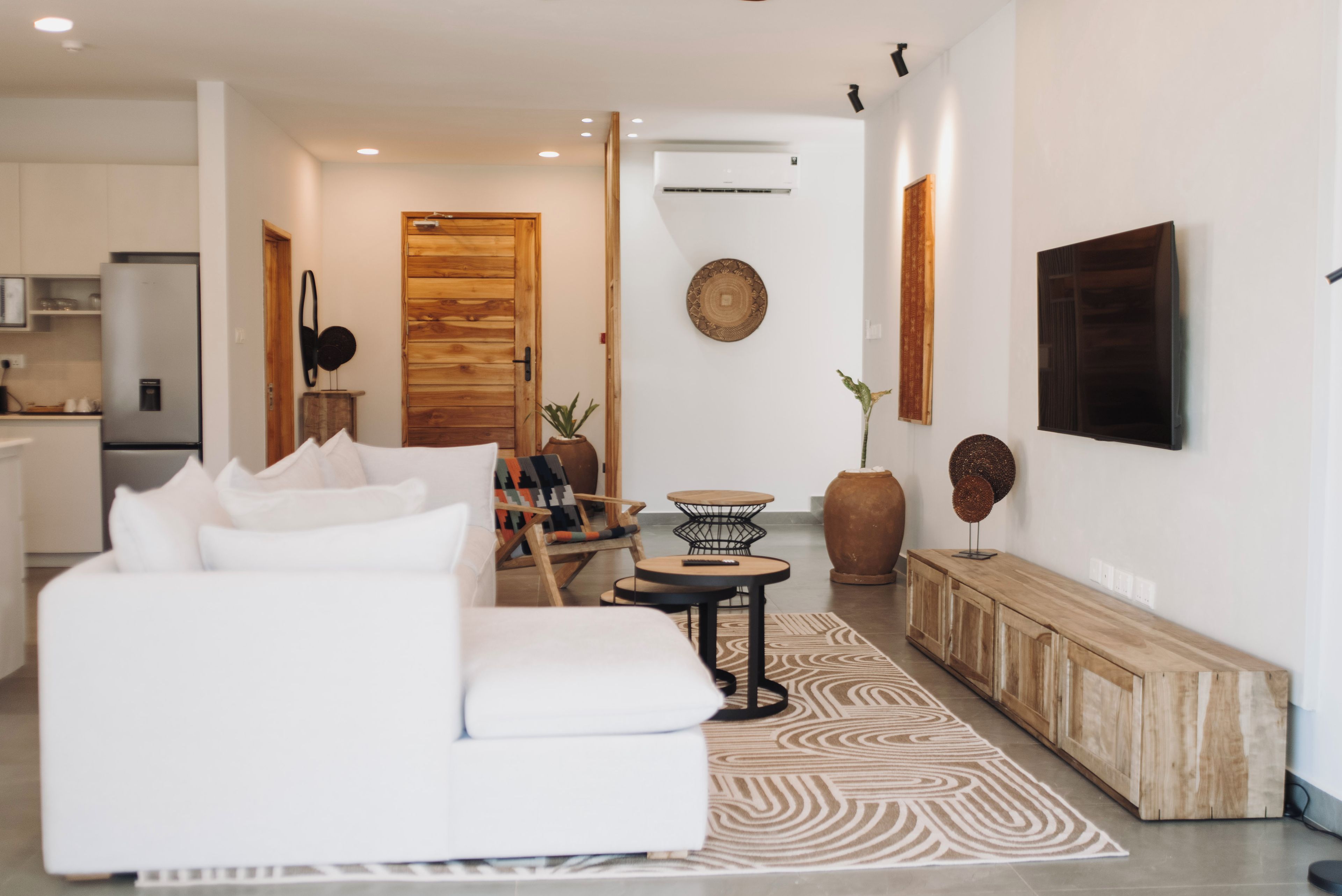 A modern living room with a white sofa, a wooden door, a small round table, and a large vase.
