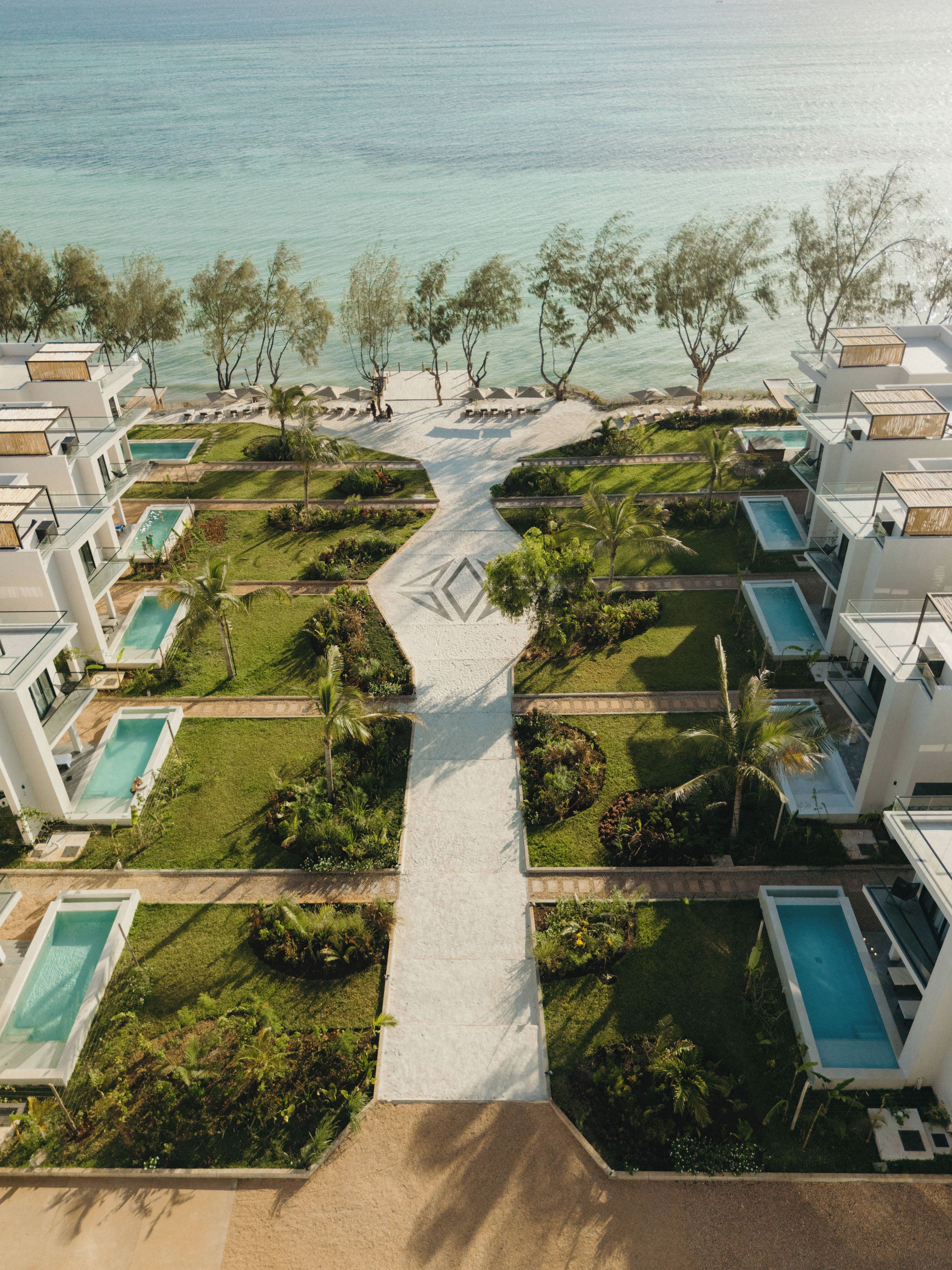 Um resort com várias piscinas, um caminho central e uma área de praia.