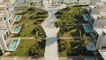 Um resort com várias piscinas, um caminho central e uma área de praia.