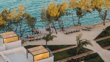 Resort à beira-mar com espreguiçadeiras, área de piscina e vista para o mar azul-turquesa.