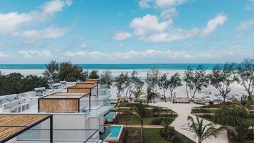 A modern resort with multiple swimming pools, a beach view, and a tropical garden.