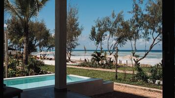 A pool area with a view of the beach and ocean.