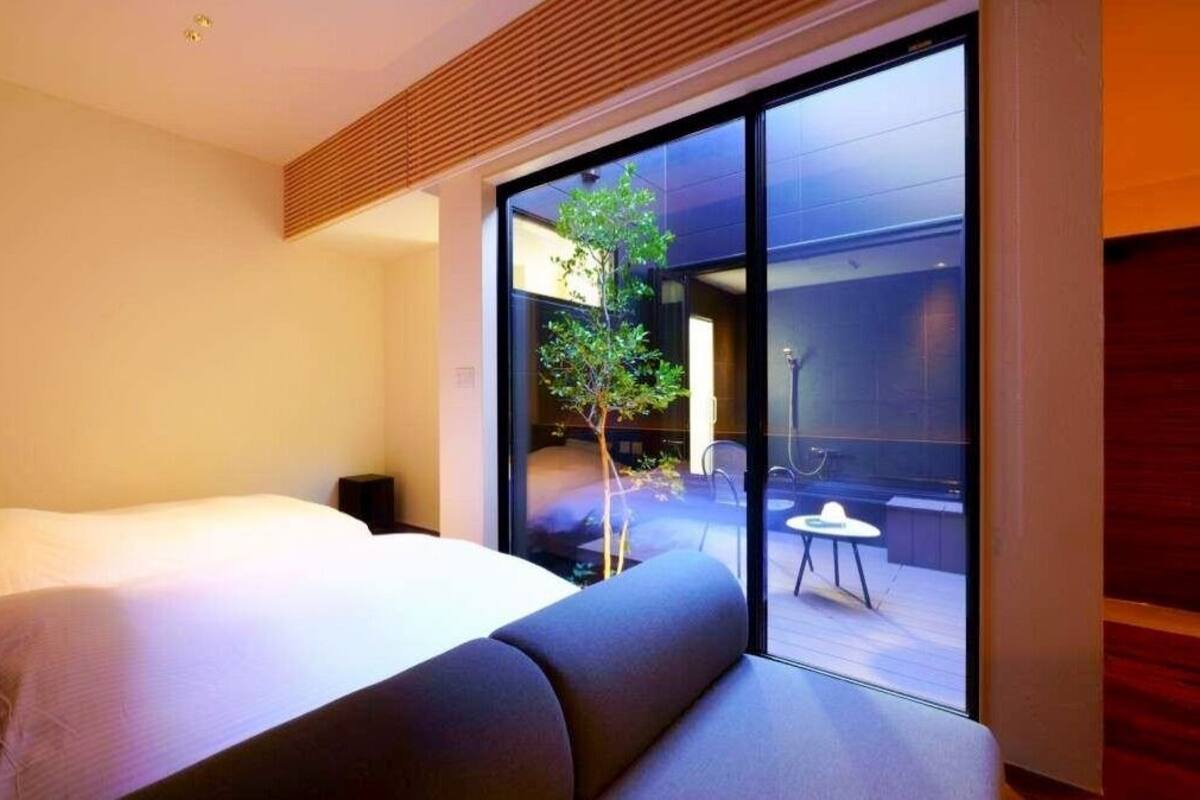 Ein modernes Hotelzimmer mit Bett, kleinem Tisch und Blick auf eine Terrasse.