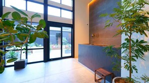 Ein modernes Interieur mit großen Fenstern, einer Rezeption und Zimmerpflanzen.