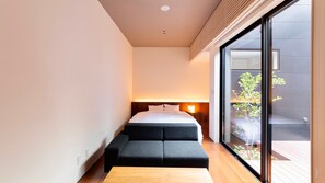 Ein modernes Schlafzimmer mit einem Bett, einer kleinen Sitzecke und einem großen Fenster.