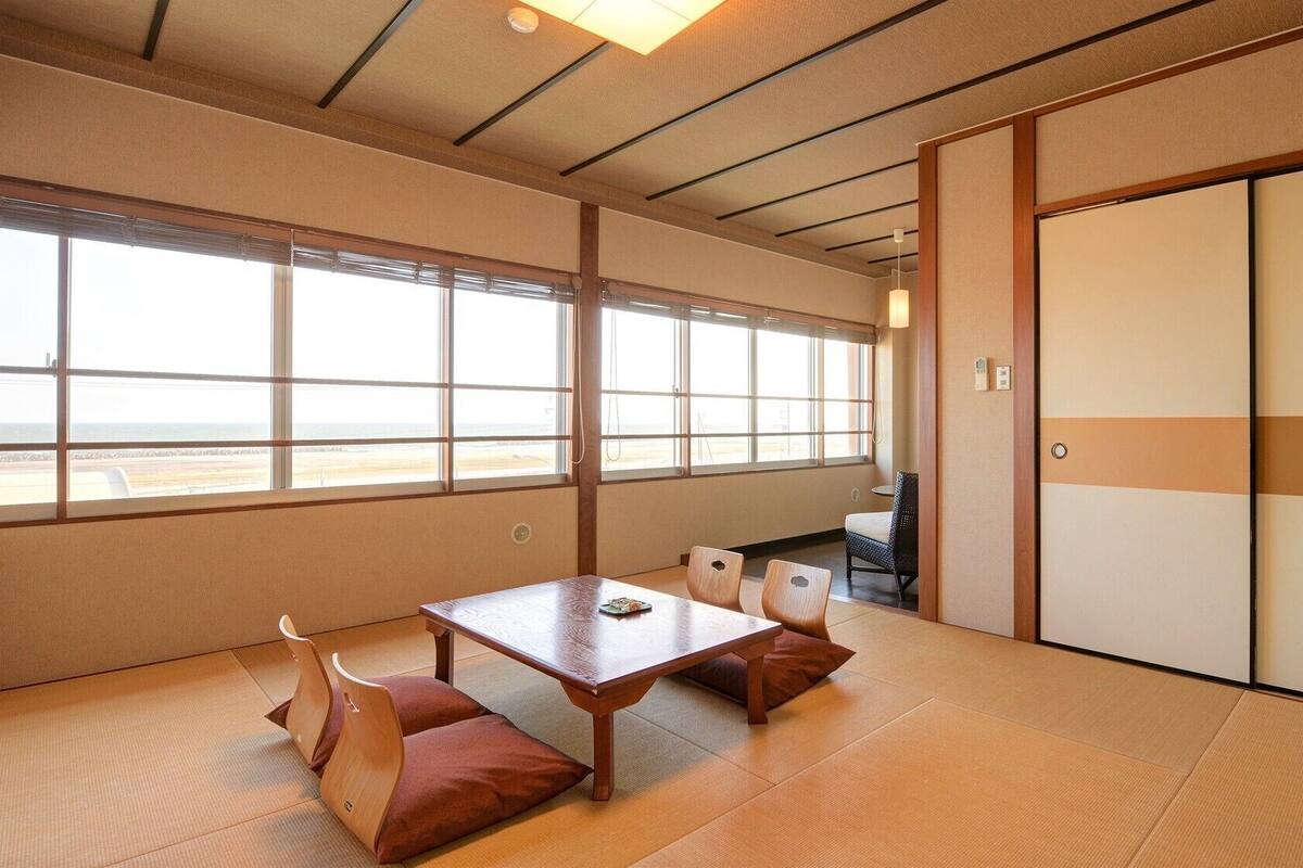 Una habitación tradicional japonesa con suelo de tatami, una mesa baja y puertas correderas.