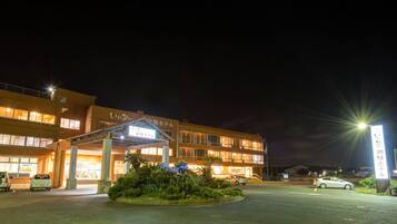 A hotel with a covered entrance, multiple floors, and illuminated windows.